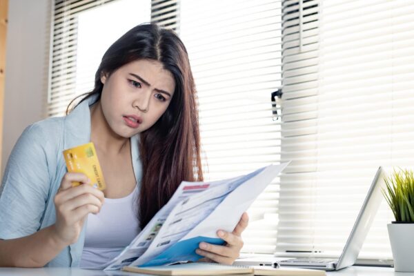 Young woman shocked and stressed over credit card debt collection documents. Financial problem concept.
