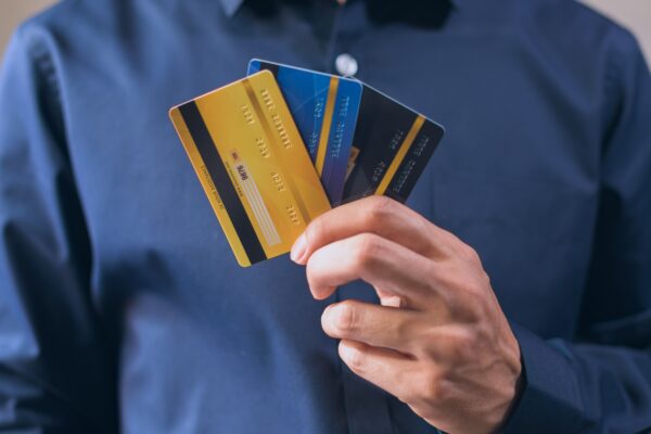 Person holding three credit cards, symbolizing finance, security, and e-commerce.