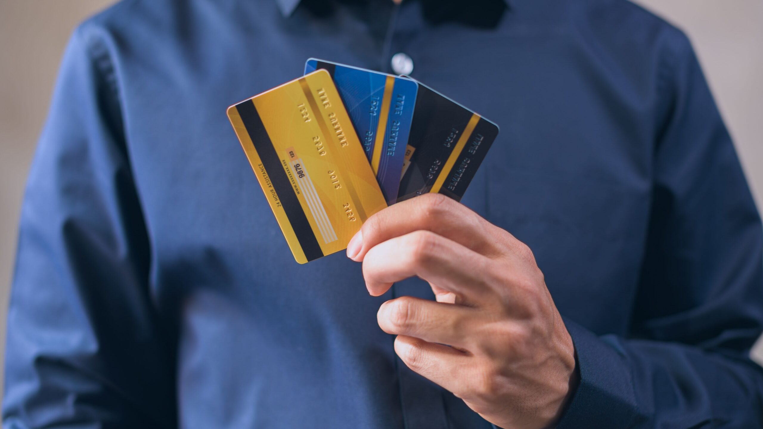 Person holding three credit cards, symbolizing finance, security, and e-commerce.