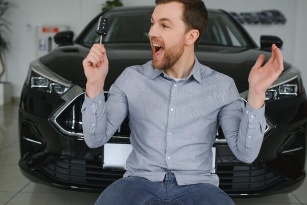 Young man is choosing a new vehicle in car dealership
