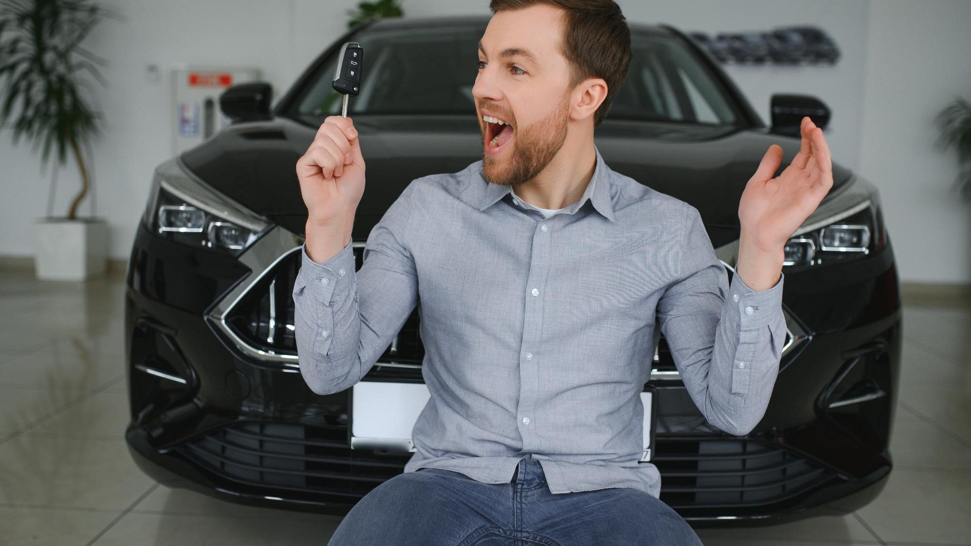 Young man is choosing a new vehicle in car dealership