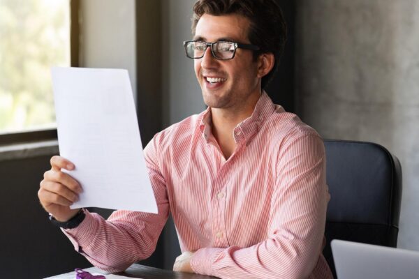 Happy millennial businessman reading correspondence in office