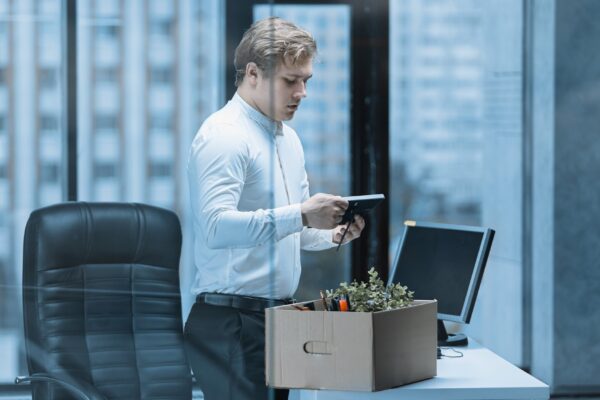 Close-up of a young office worker packing his things in a box after being fired