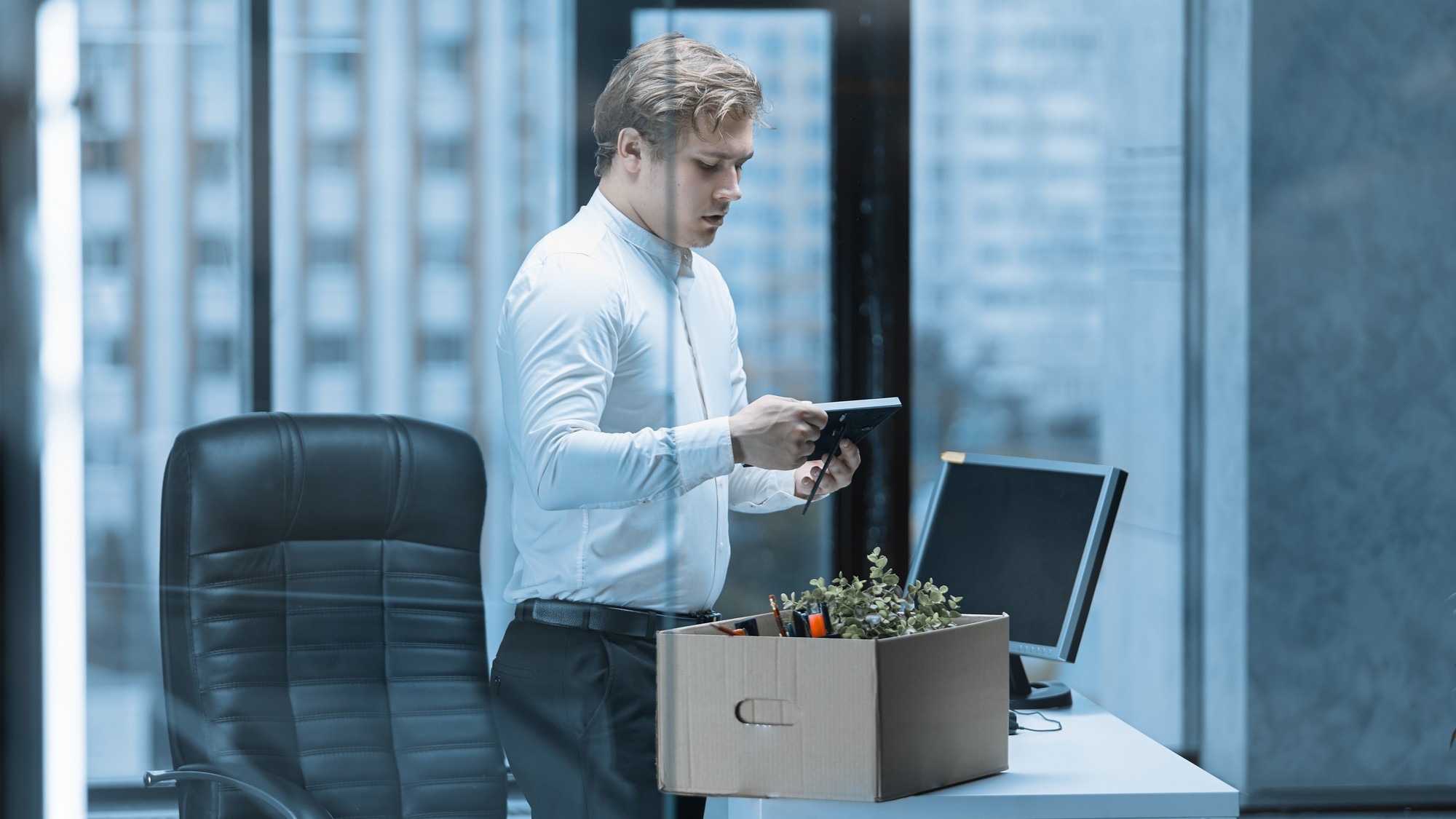 Close-up of a young office worker packing his things in a box after being fired