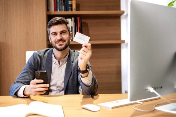 Company manager sitting in his office and holding business card