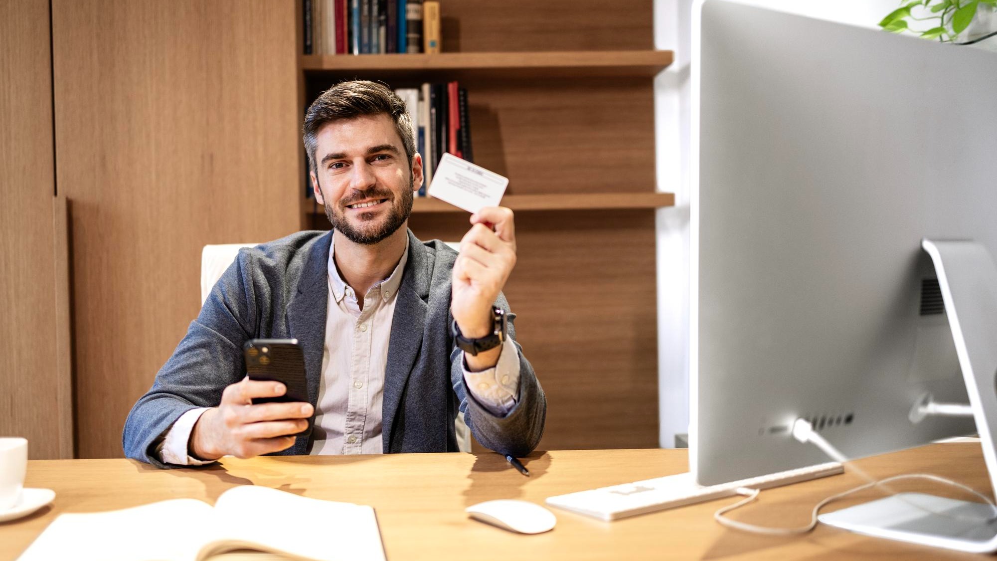 Company manager sitting in his office and holding business card