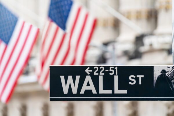 Wall street sign in New York city financial economy and business district with America national flag background. Stock market trade and exchange zone.