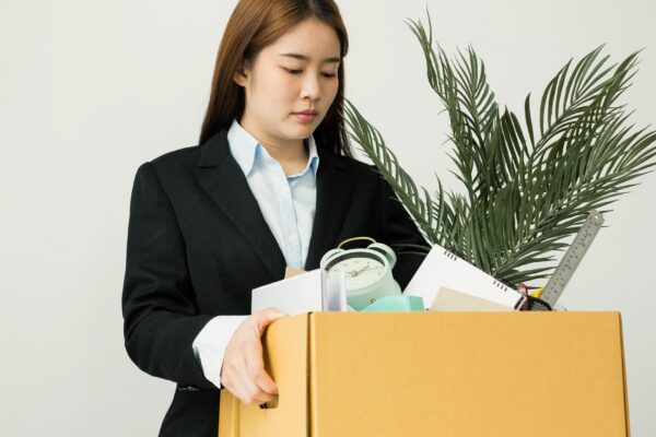 Portrait of businesswoman holding box against white background