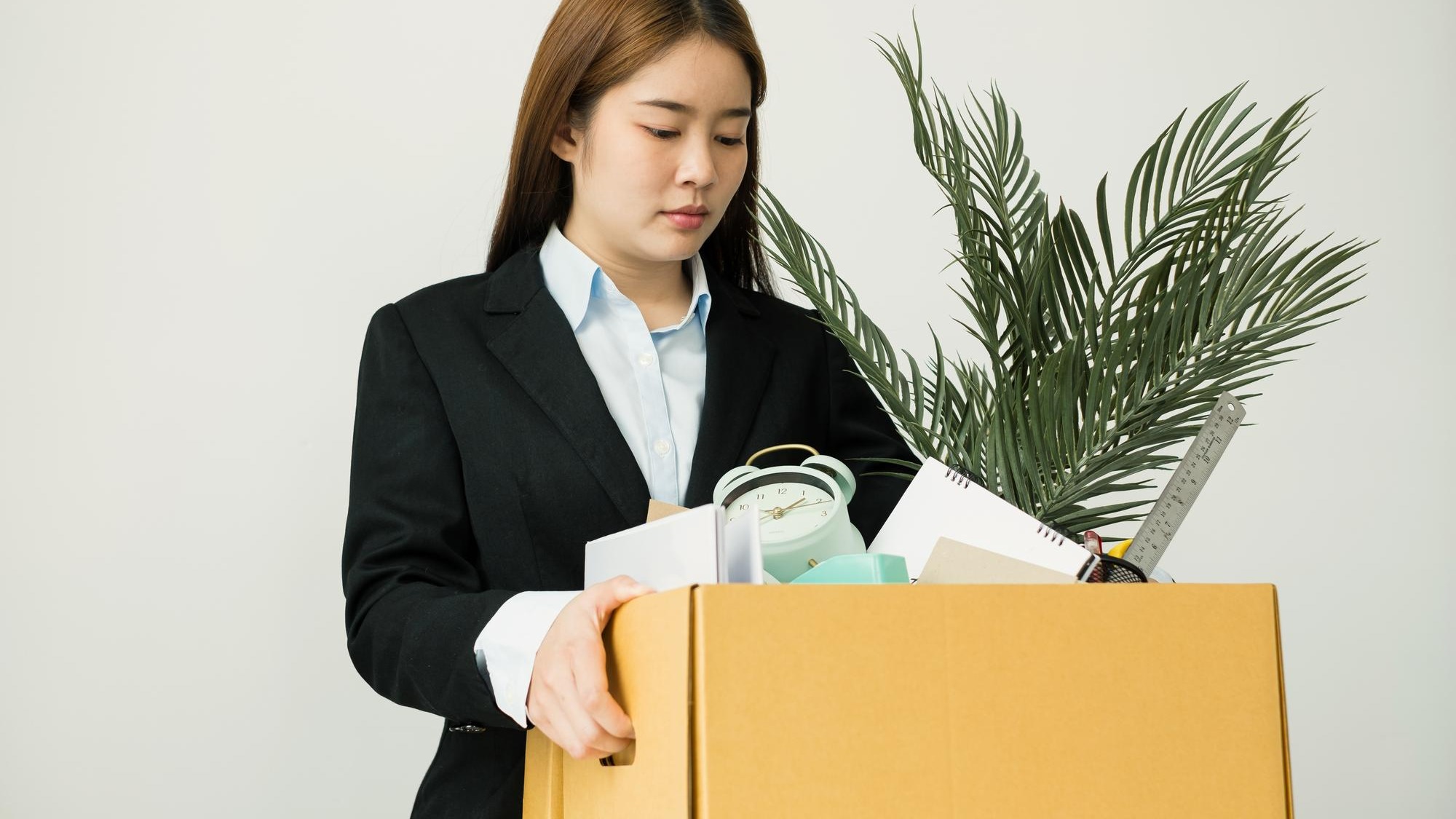Portrait of businesswoman holding box against white background