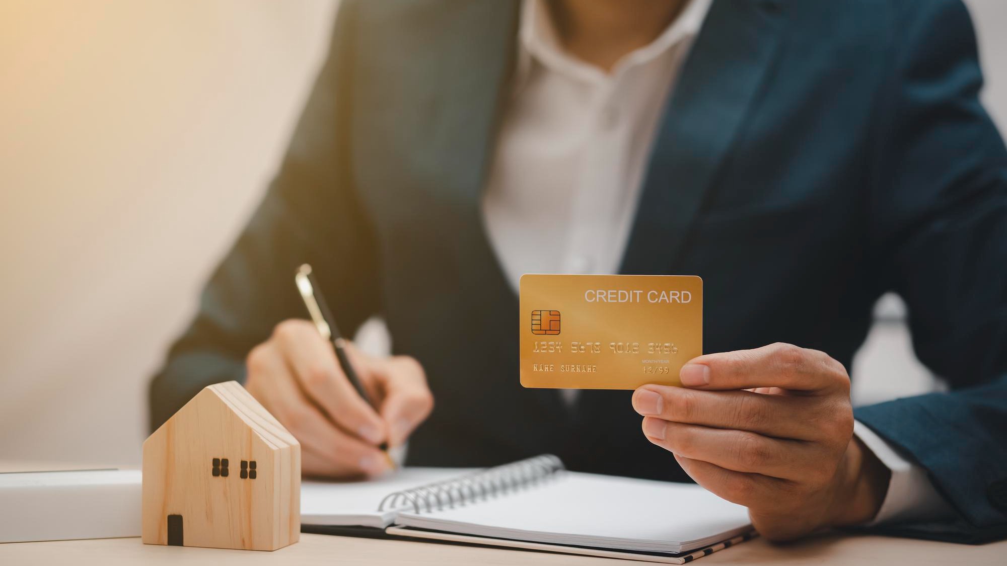 Businessman hand write note on paper with hold credit card with financial transaction with credit card and laptop computer, Online shopping concept, banking and online shopping at the home.