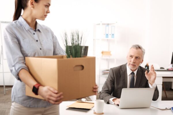 Young office worker feeling sadness, bowing her head while looking at her boss