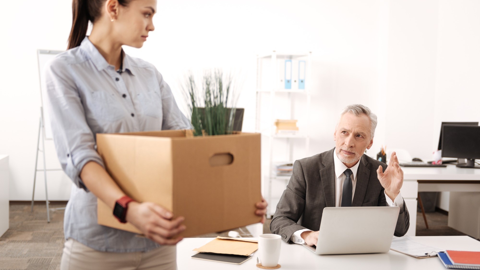 Young office worker feeling sadness, bowing her head while looking at her boss