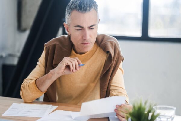 Busy day A darkhaired man sitting at the table and working with documents