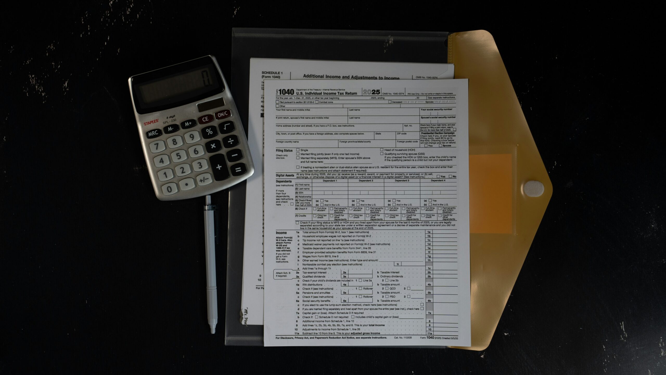 Calculator and papers in a folder on a dark surface
