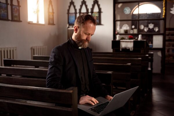 Close up on priest using laptop