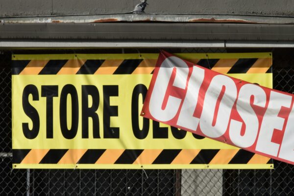 A store closed sign hanging from the side of a building