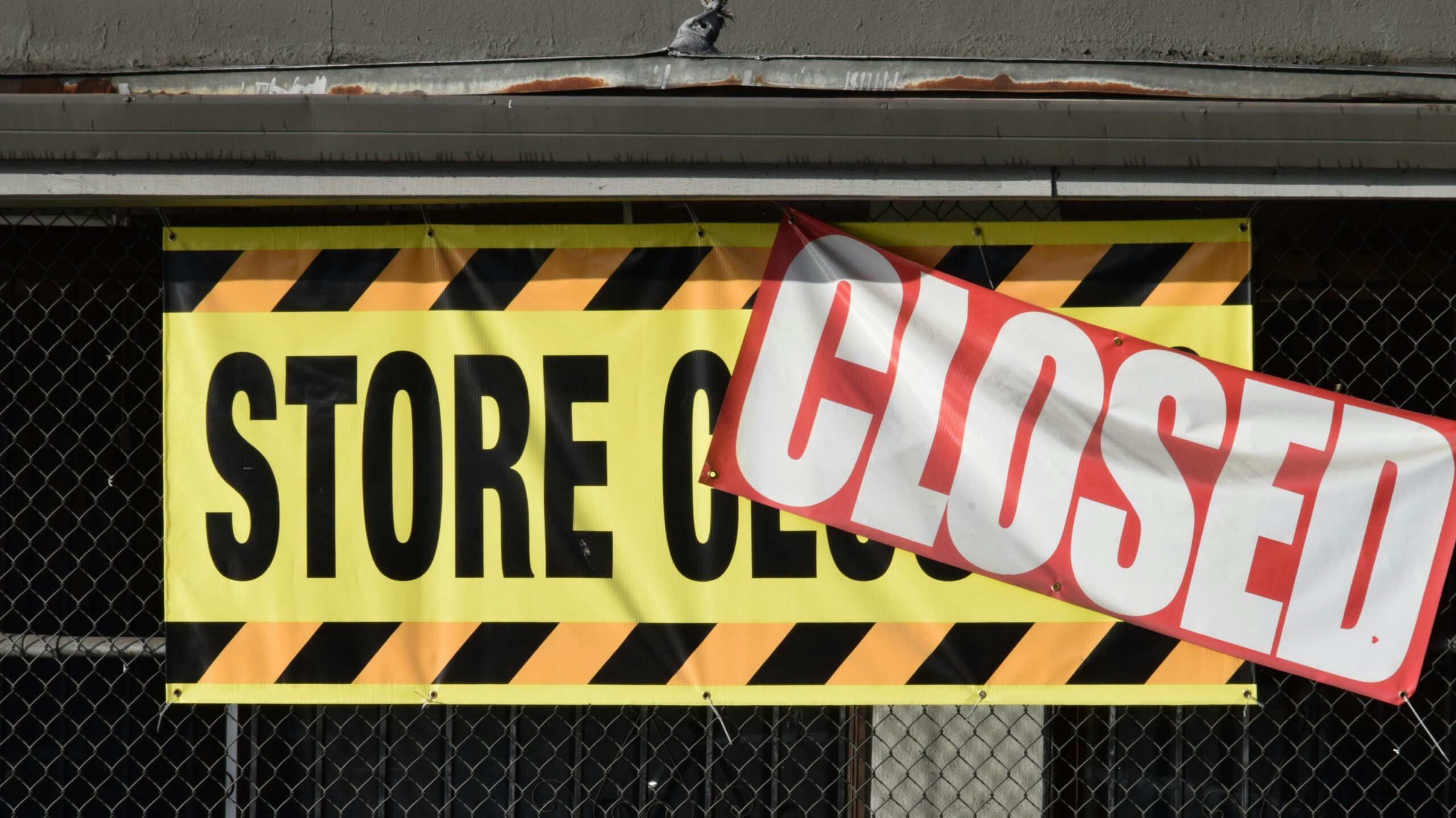 A store closed sign hanging from the side of a building
