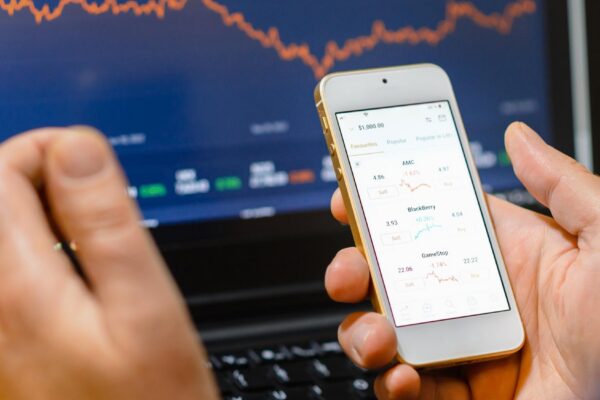Trade and finance conceptBusinessman checking stock market by his smartphone and laptop screenscreen analyzing financial stock market trading data chartsTelsiaiLithuania03302023