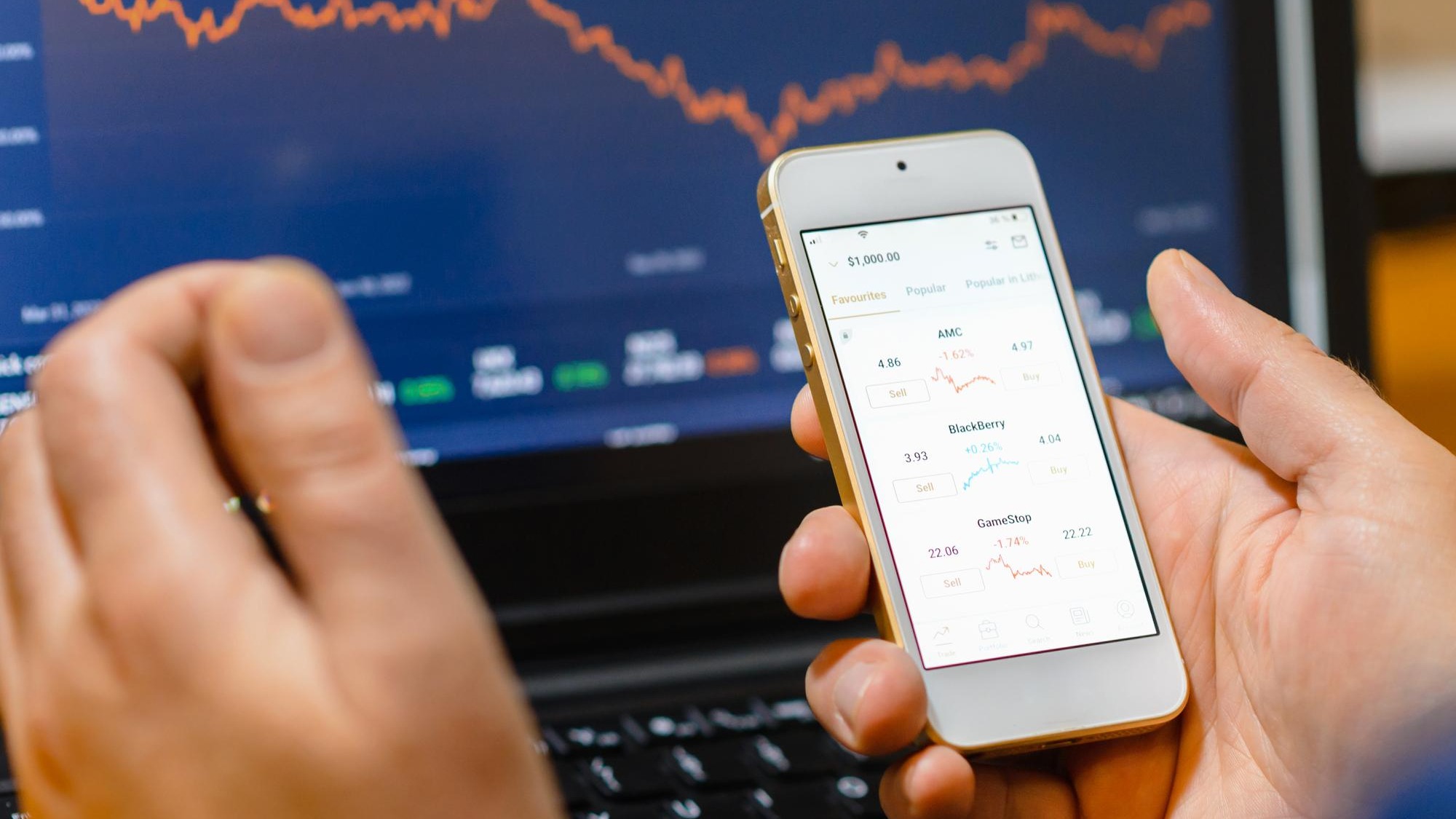 Trade and finance conceptBusinessman checking stock market by his smartphone and laptop screenscreen analyzing financial stock market trading data chartsTelsiaiLithuania03302023