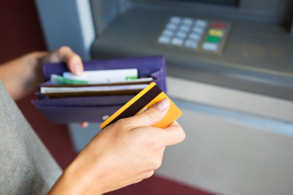 finance, money, bank and people concept - close up of hands with cash and credit card at atm machine