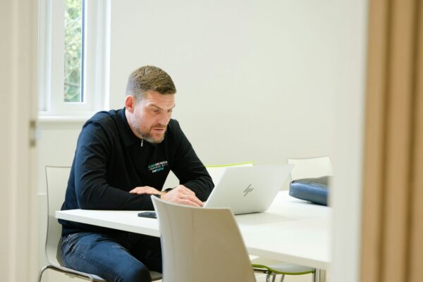 Man working on laptop at a white table.