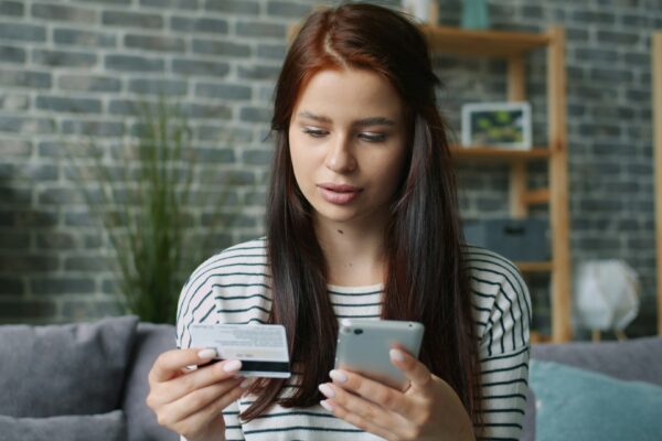 Woman holding credit card and smartphone for online shopping.