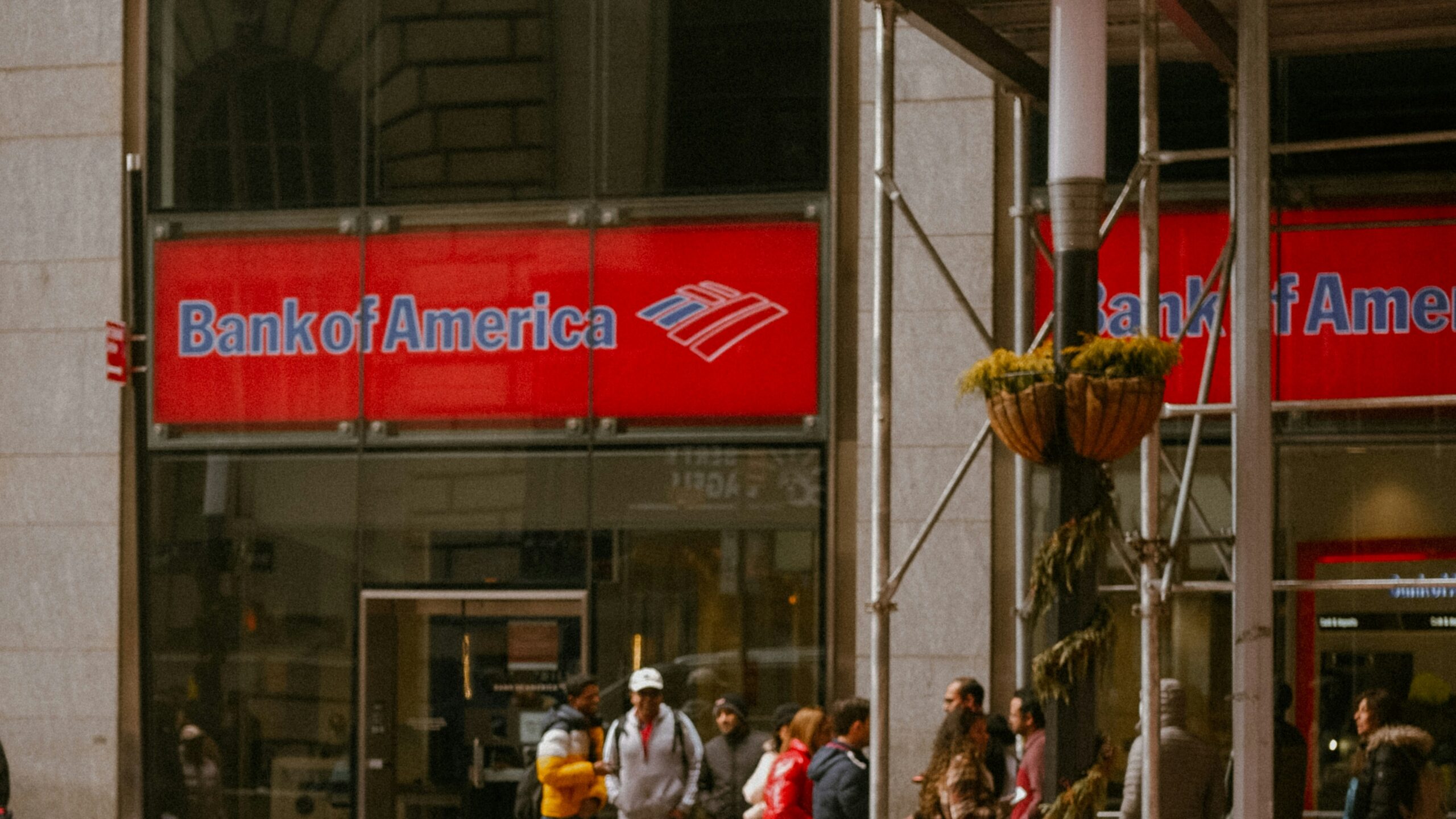 a red sports car is parked in front of a bank of america