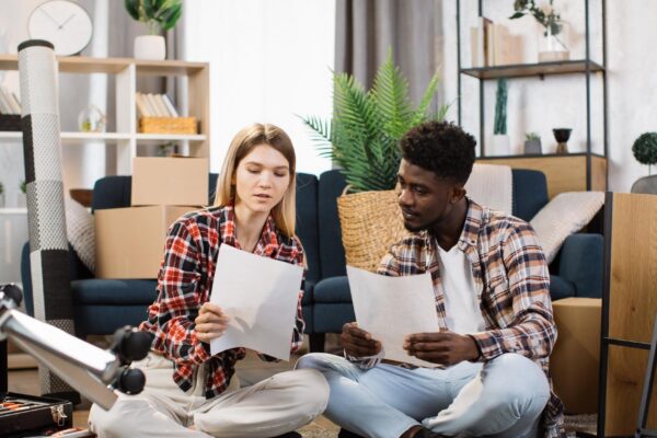 Diverse couple advising about furniture placement at flat