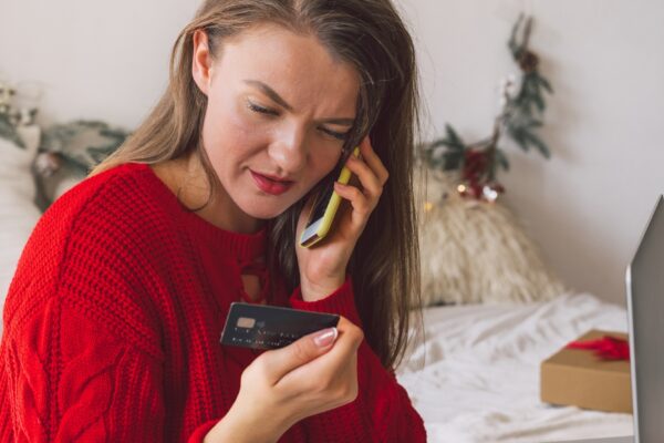 Young woman shopping online with credit card and mobile phone while laying at home. Online shopping e-commerce concept.
