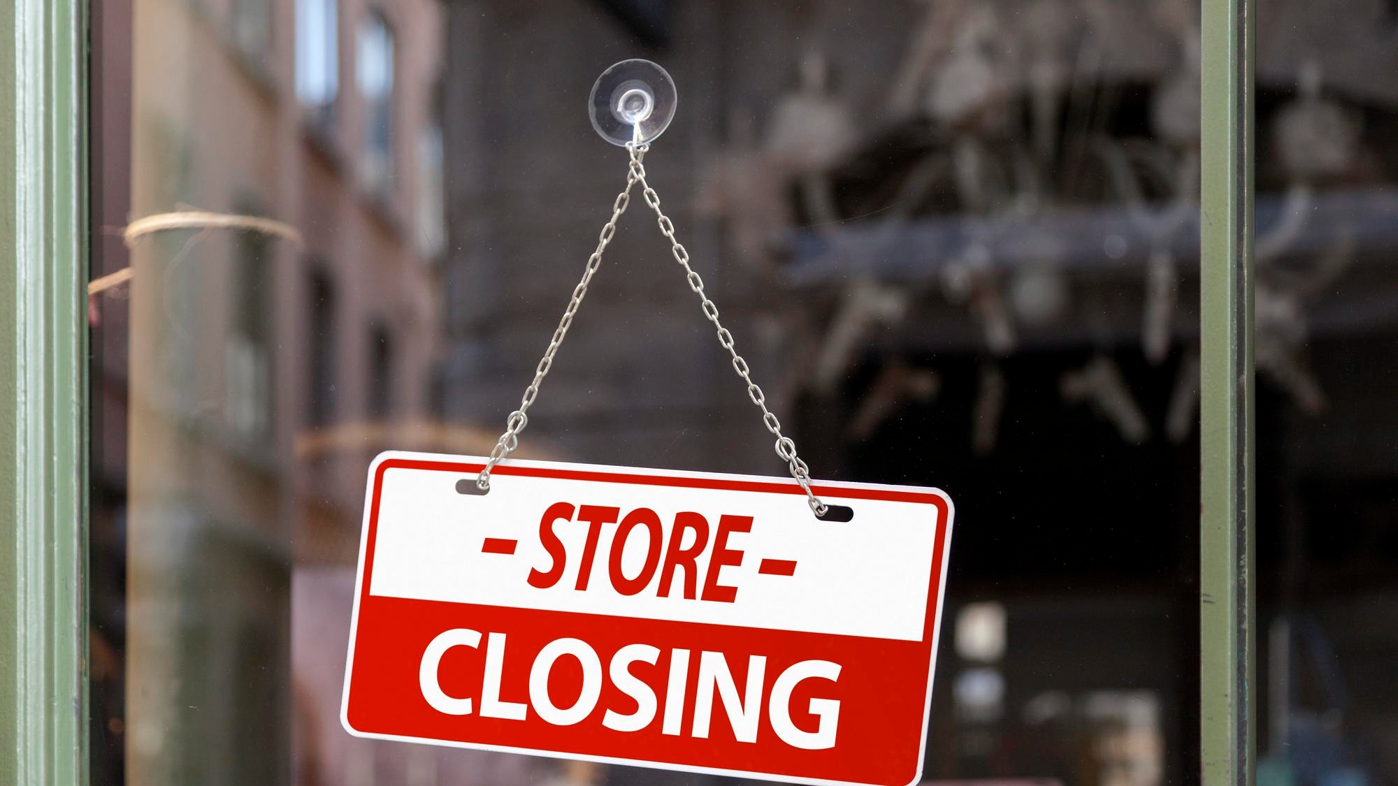 Closeup on a red sign in a window written inside in English Store closing