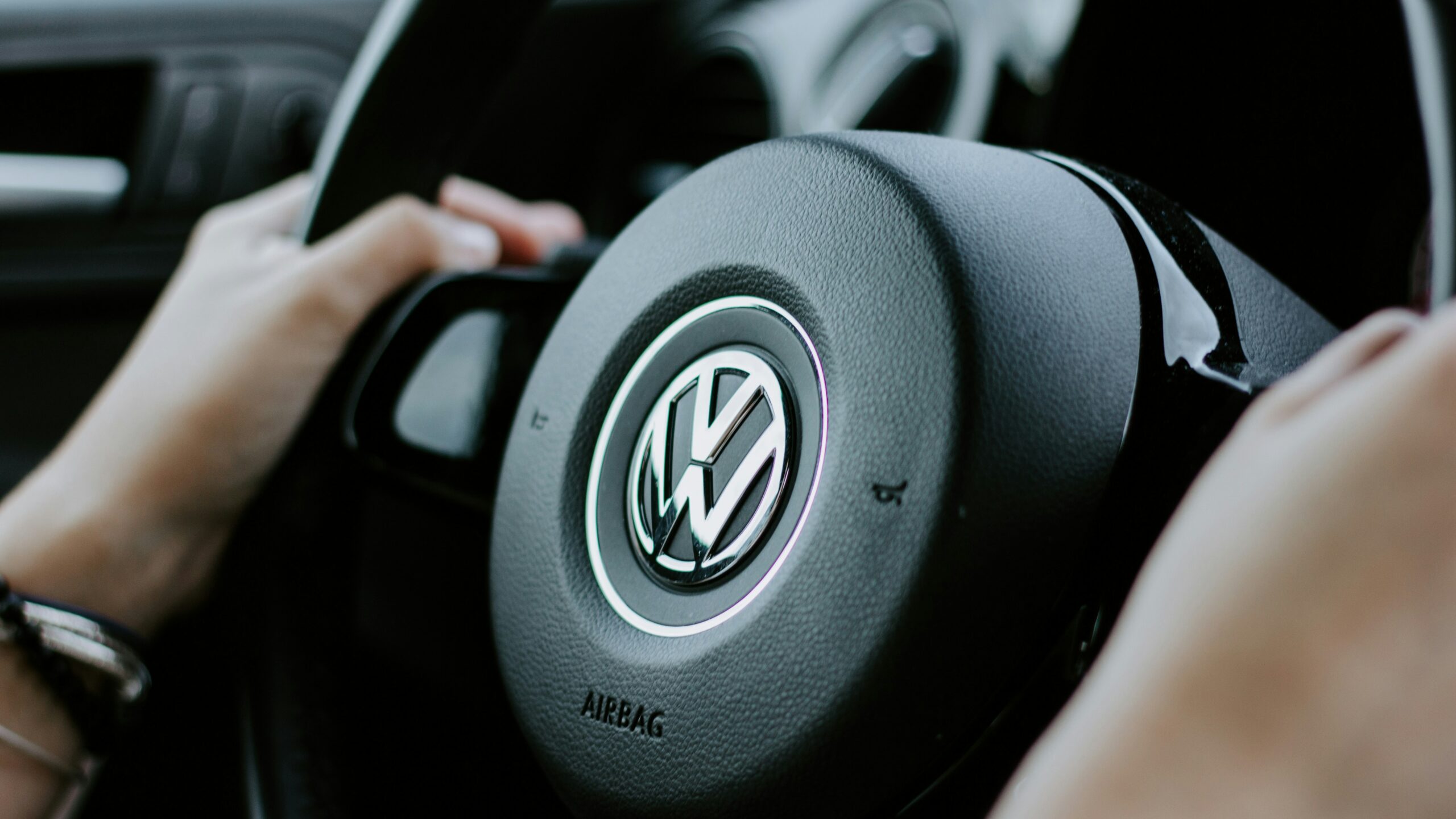person holding black Volkswagen steering wheel in closed-up photo