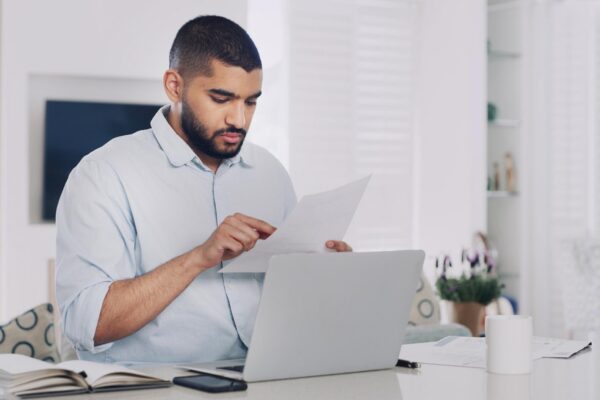 Remote work from home laptop and man with documents deadline and research for news report Person copywriting and journalist with PC editing and email for feedback reading and review for article