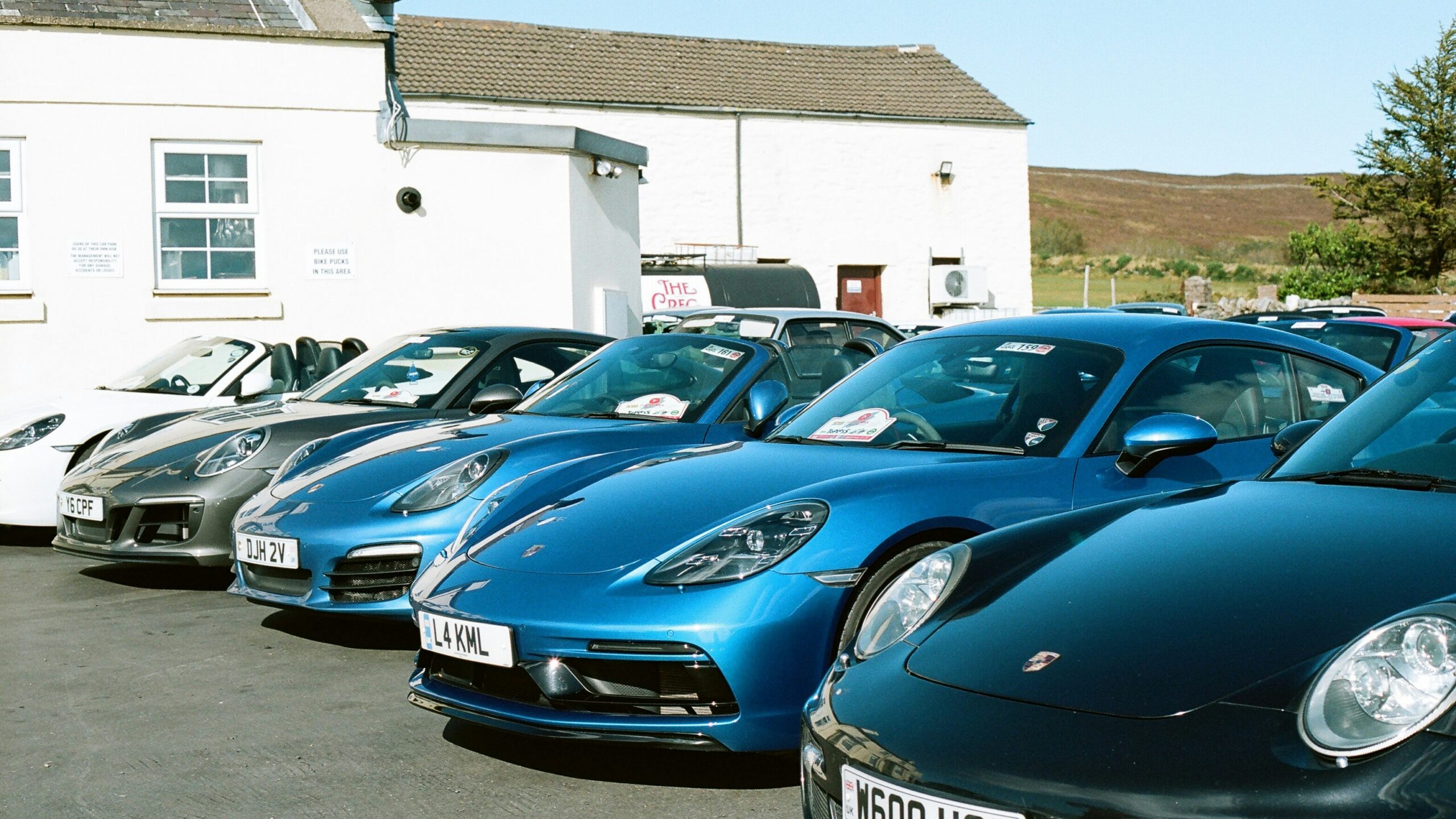 Several blue porsche cars parked in a row.