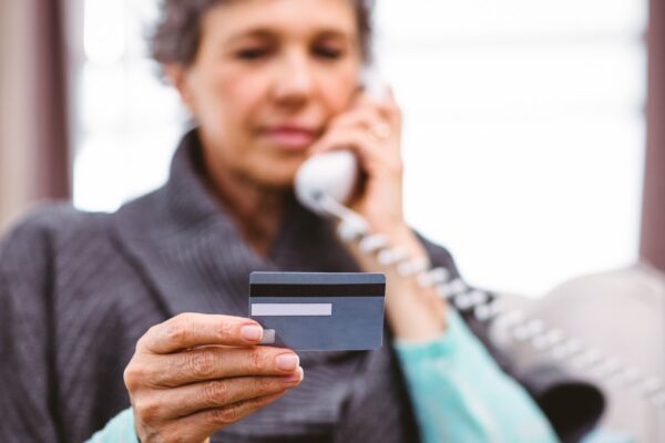 Mature woman holding credit card while talking on telephone