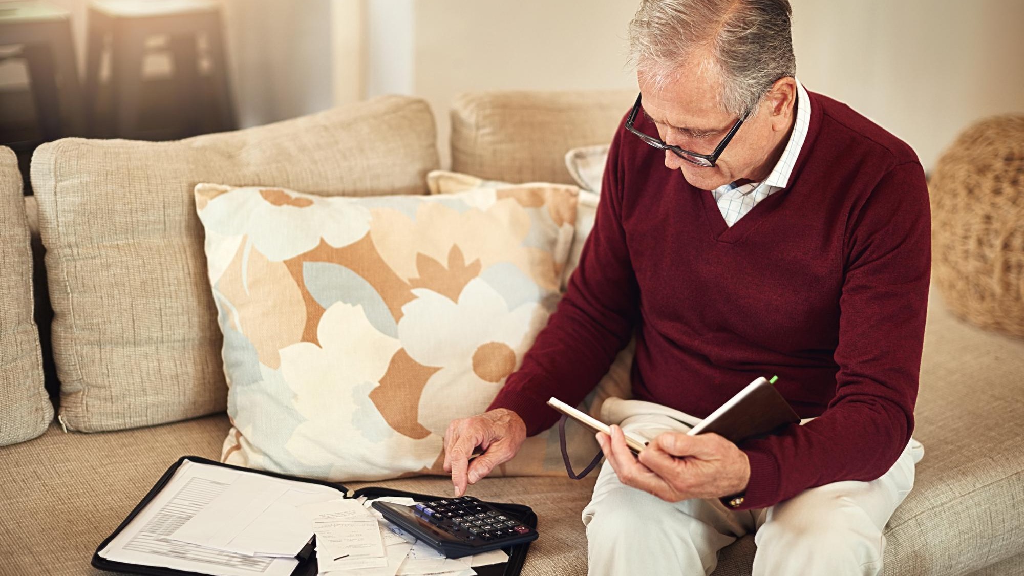 Senior man notebook and calculator on sofa for budget planning and savings account for retirement Elderly person bills and couch in lounge for mortgage personal debt and loan repayment ay home