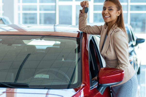 Photo of happy young woman showing key to her new car Concept for car rental