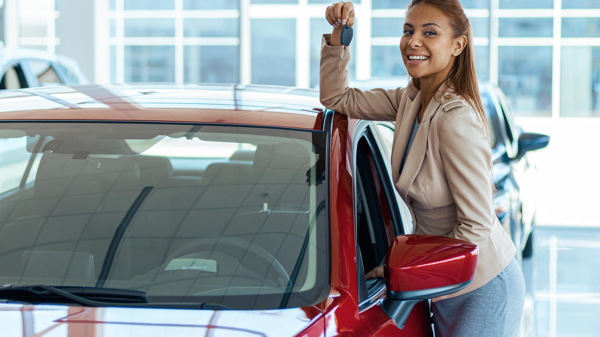 Photo of happy young woman showing key to her new car Concept for car rental