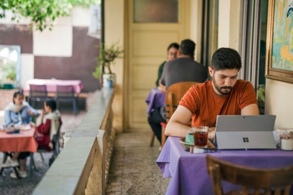Man working on laptop at outdoor cafe table