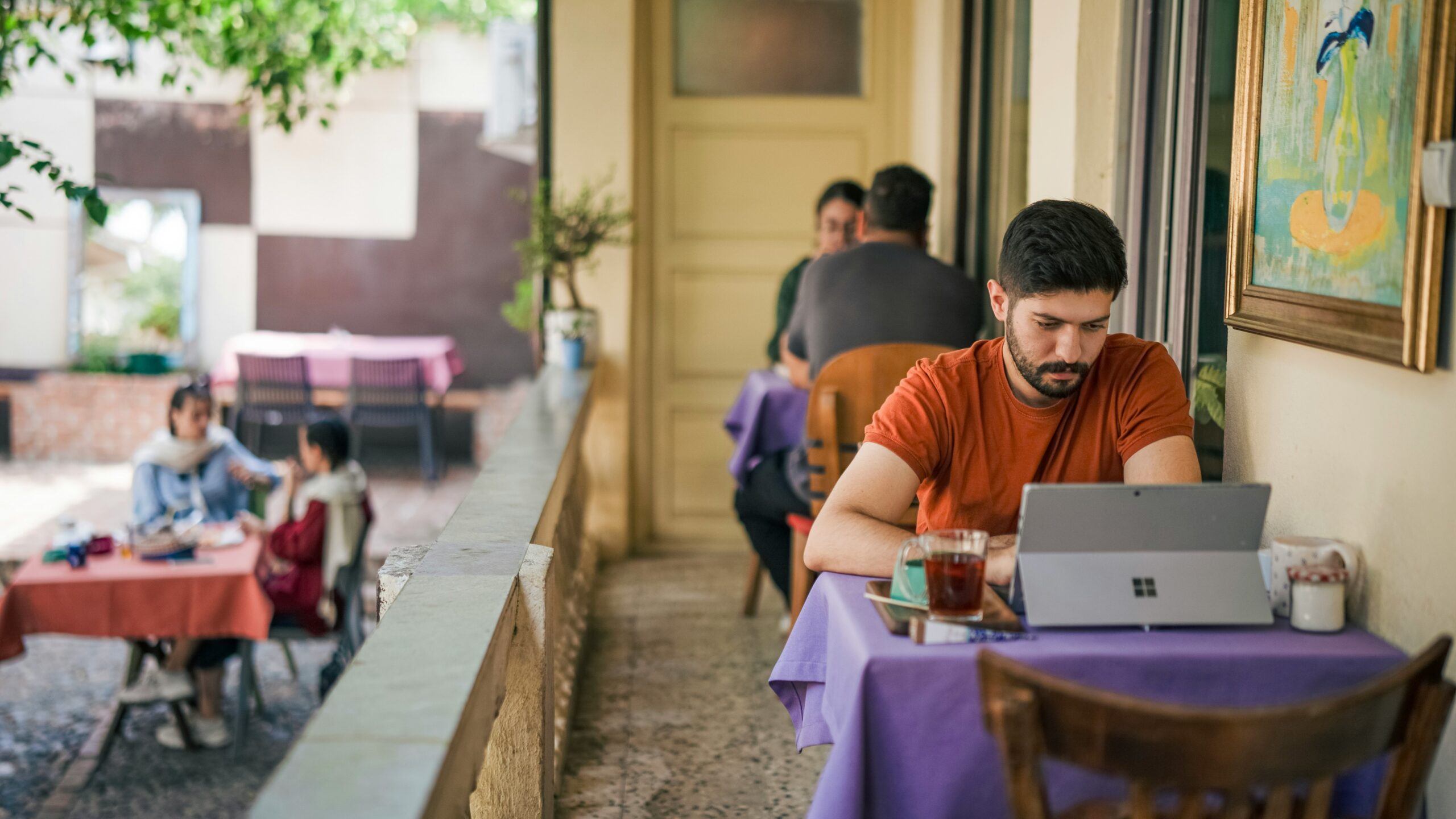 Man working on laptop at outdoor cafe table