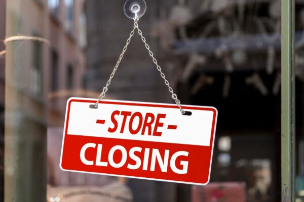 Closeup on a red sign in a window written inside in English Store closing