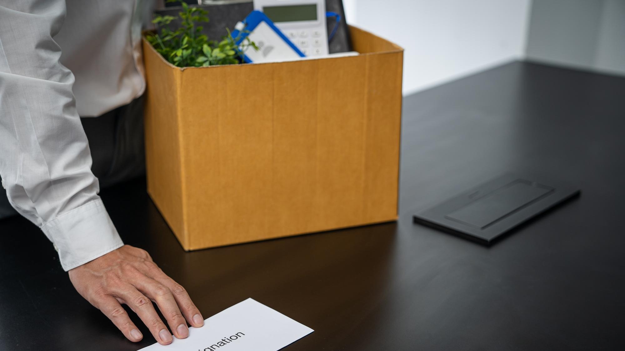 Business man sending resignation letter and packing Stuff Resign Depress or carrying business cardboard box by desk in office Change of job or fired from company