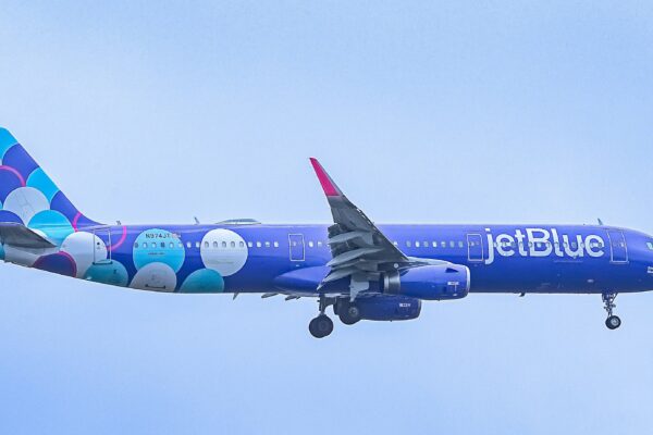 A blue jetblue airplane flying in the sky.