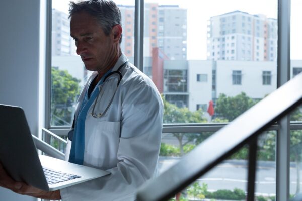 Male doctor using laptop while walking on stairs