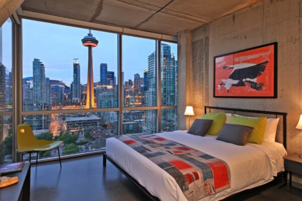 Modern bedroom with city skyline view at dusk