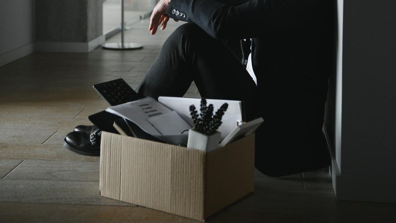 Sad fired businessman sitting outside meeting room after being dismissed
