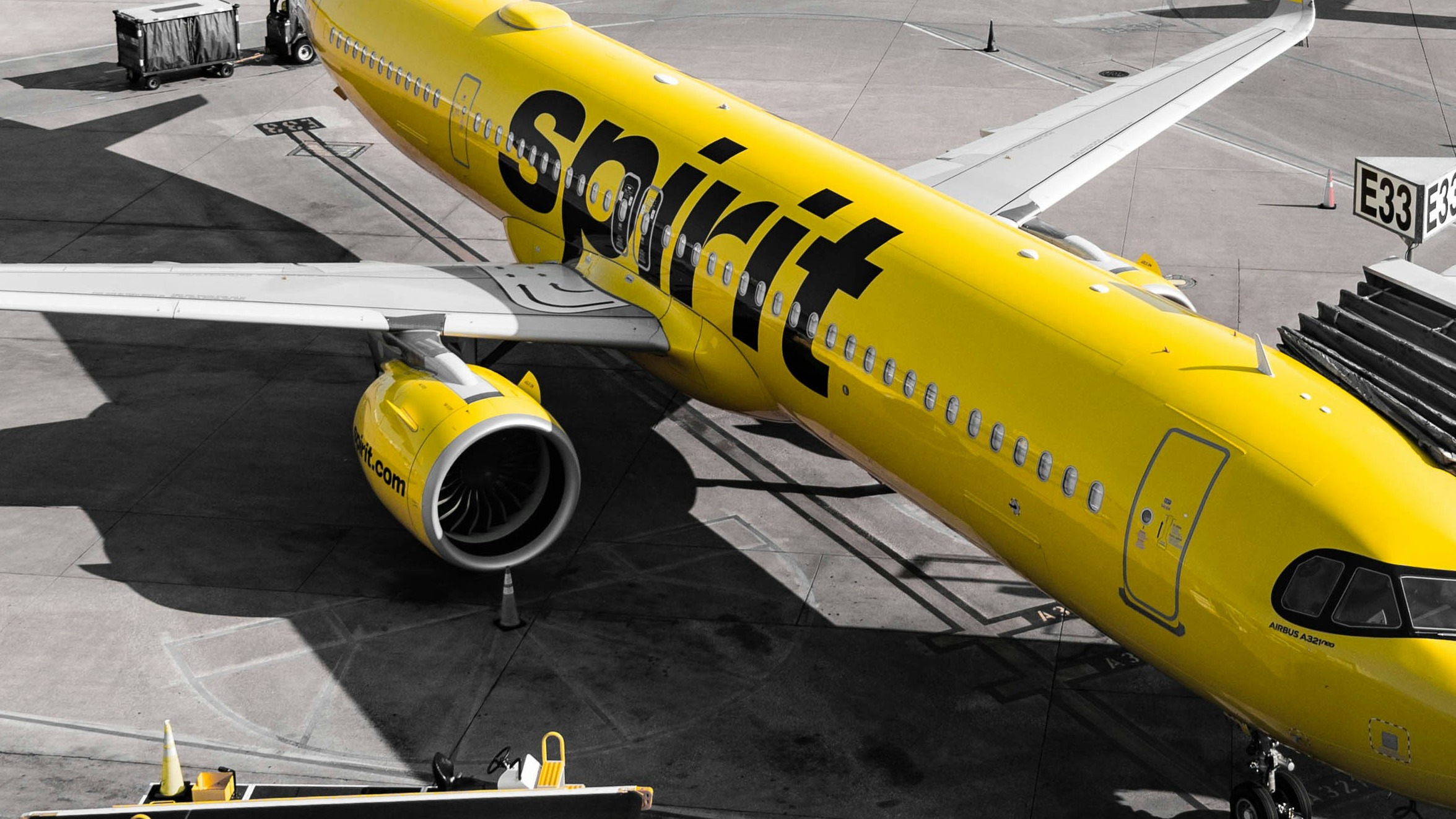 A yellow spirit airlines airplane at the gate.