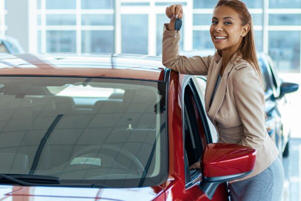 Photo of happy young woman showing key to her new car Concept for car rental