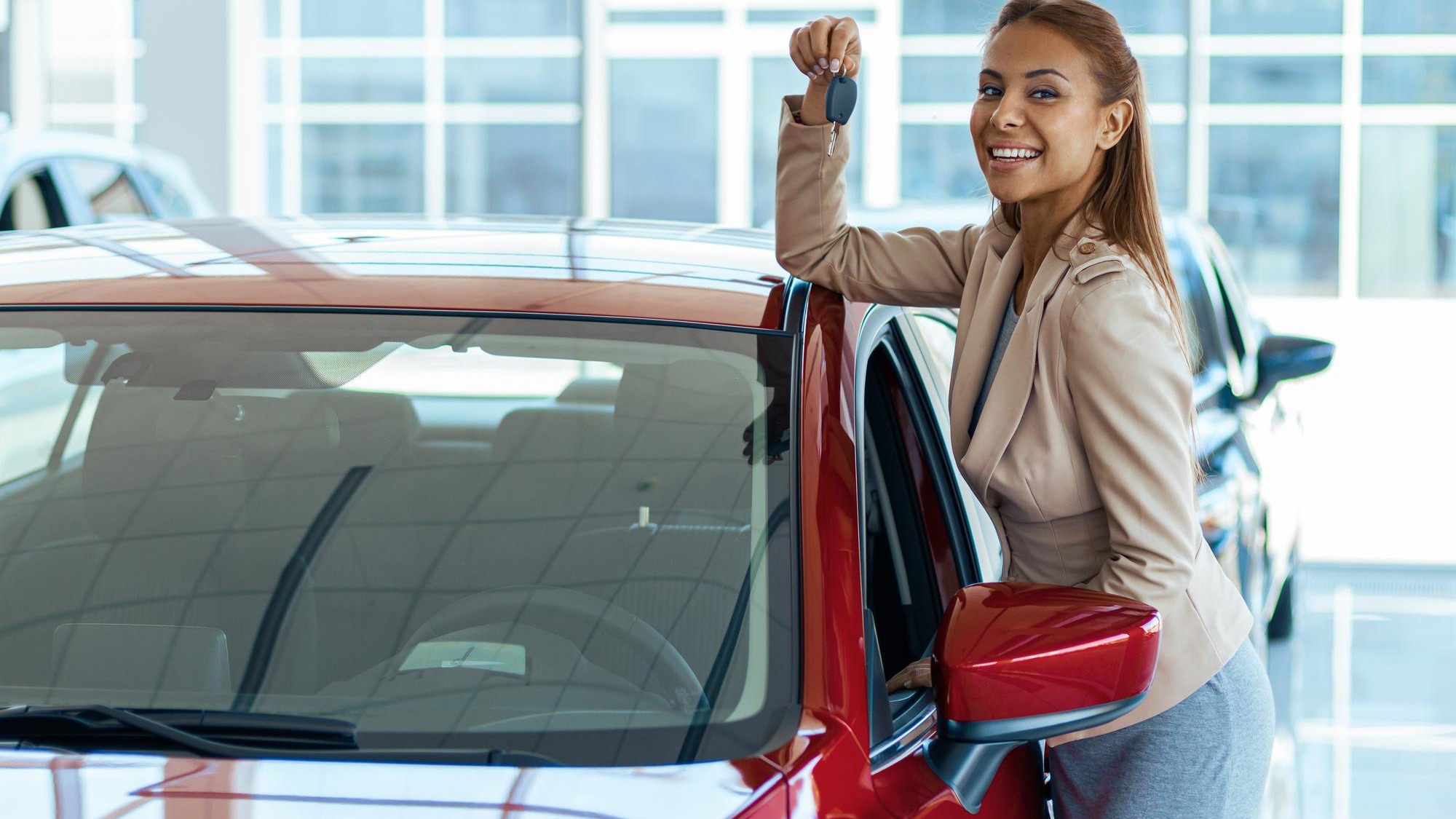 Photo of happy young woman showing key to her new car Concept for car rental