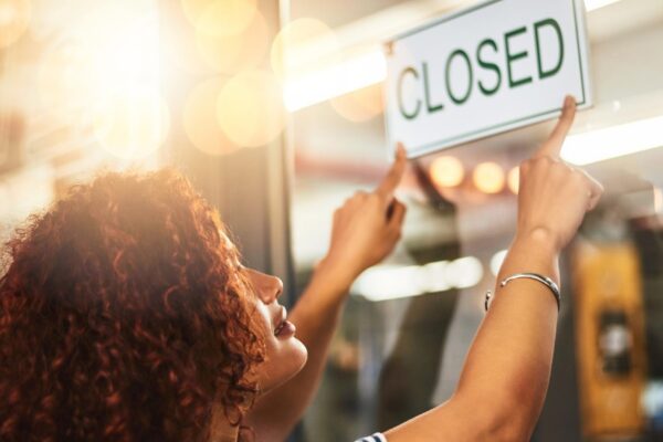 Its the end of another successful day Shot of a young woman hanging up a closed sign in her store