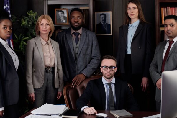 A diverse group of business professionals posing in an office, showcasing teamwork and leadership.